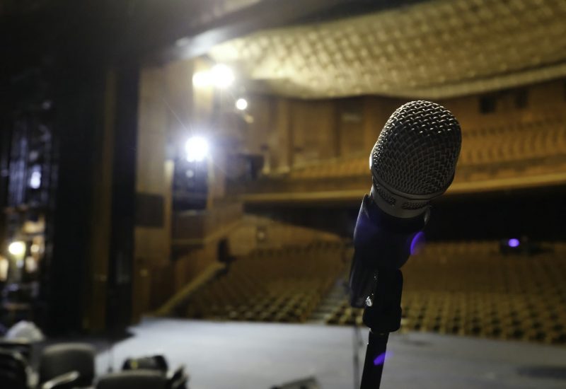 Microphone on the stage and empty hall during the rehearsal. Microphone on stage with stage-lights